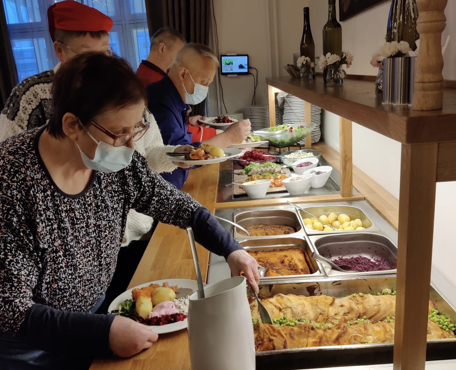 Ihmisiä ottamassa ruokaa jouluisesta noutopöydästä.