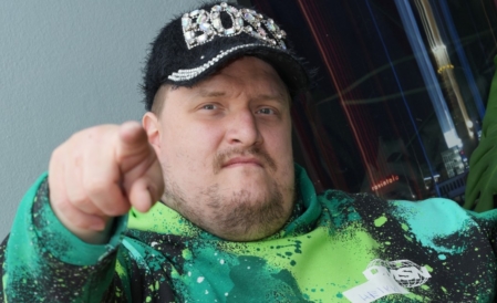 Mies katsoo kameraan ja osoittaa sormella.