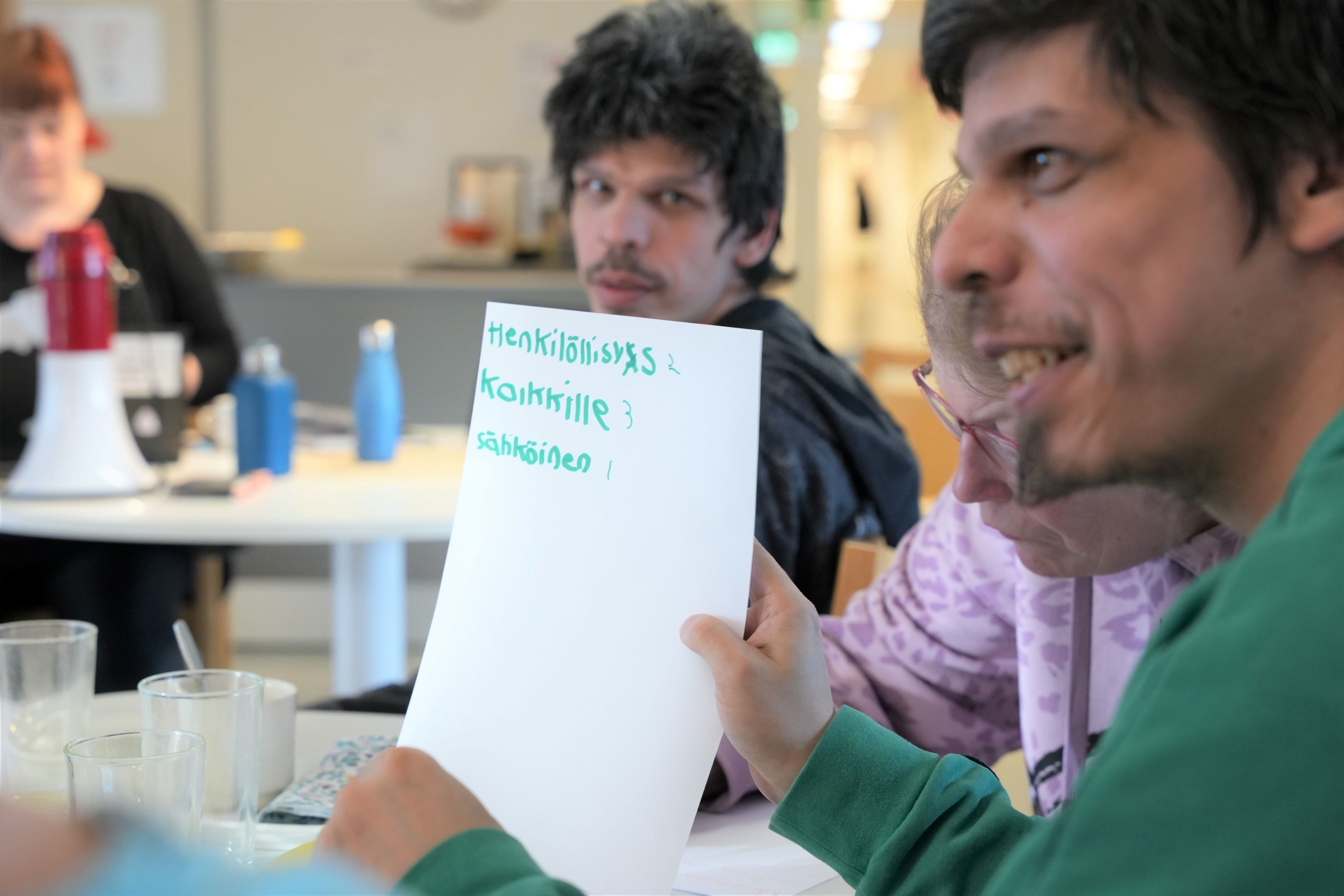 Henkilö näyttää paperia, jossa tekstiä.